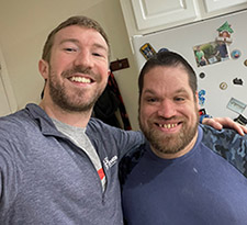 two men smile at the camera with their arms around each other