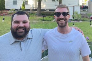 two bearded men embrace while smiling for the camera